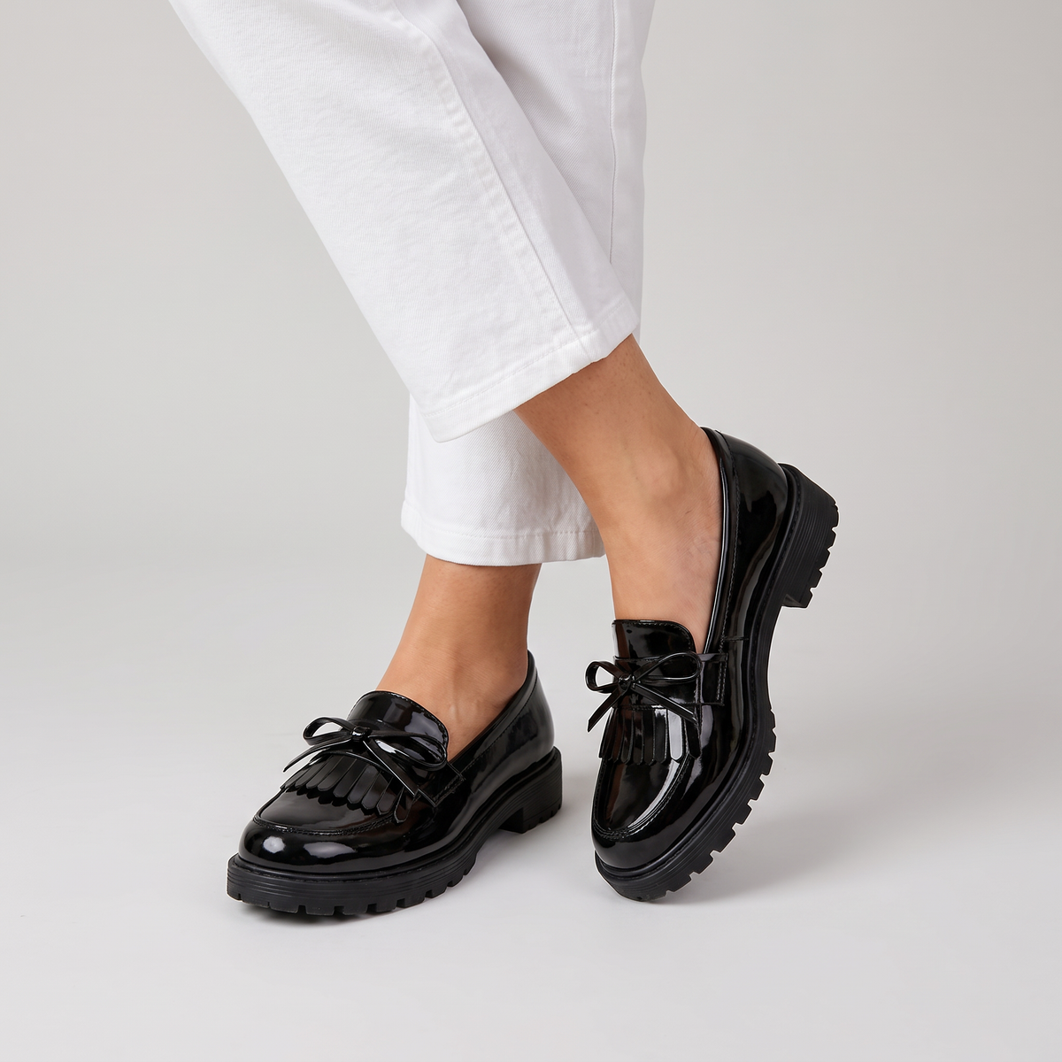 Cailie glossy lug sole loafers with fringe and bow worn